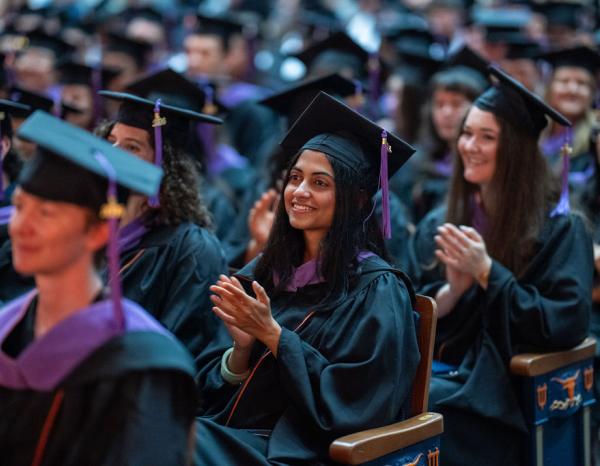 Graduates clapping at a commencement ceremony