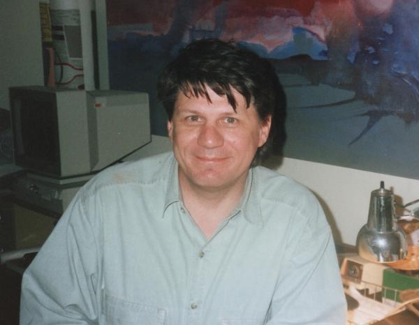 A photo of Michael Garrison in 1992, with one of his paintings in the background