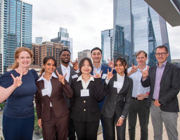 A group of students and faculty in front of the Austin city skyline
