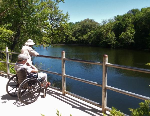 Older couple, one in a wheelchair, looking out onto one of Austin's waterways