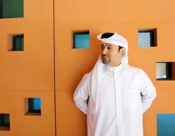 Dr. Khaled Alawadi standing next to orange wall