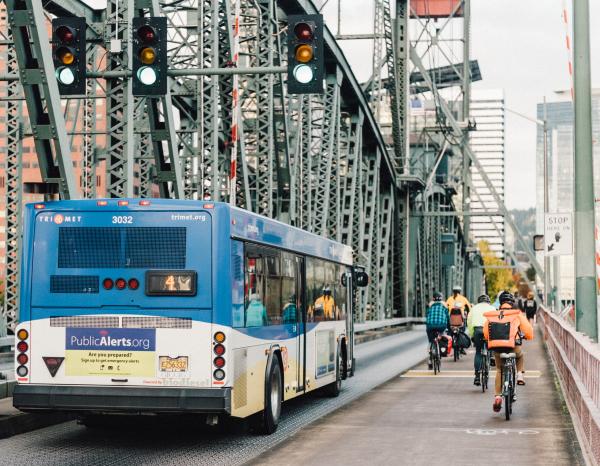 Bicyclists ride alongside a blue bus in downtown Portland