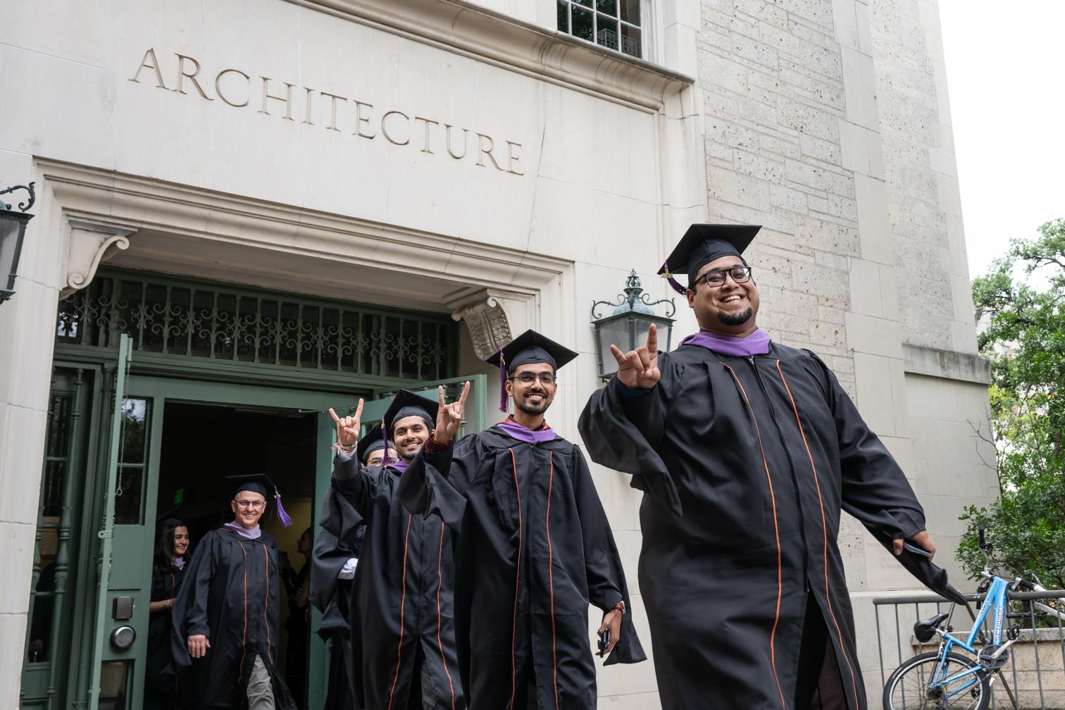Students in regalia exiting the architecture building.