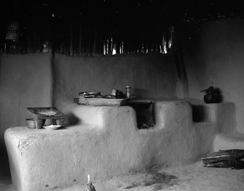 Black and white photograph of large concrete shelves with cooking utensils.
