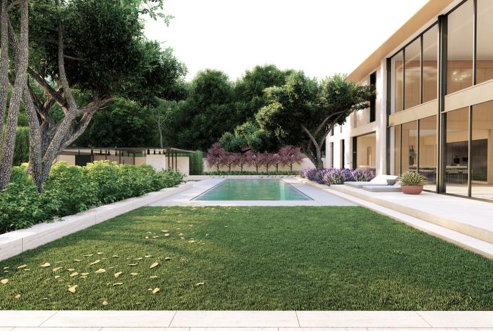 Exterior shot of a pool with a grassy area in the foreground, trees and bushes to the left and a windowed facade on the right