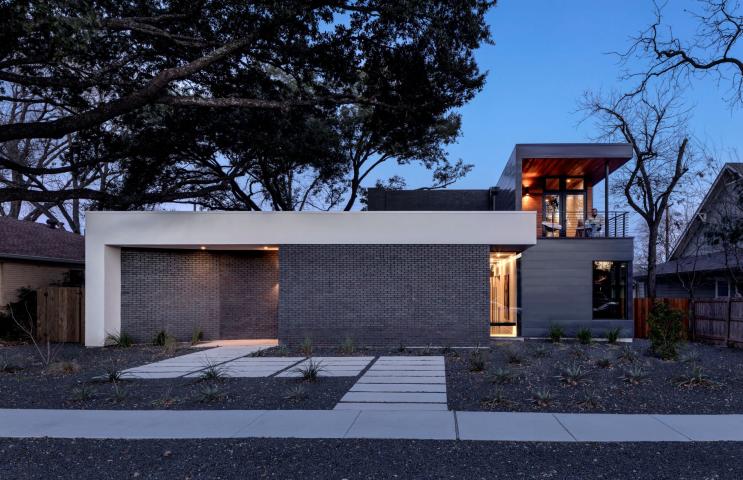 Front facade of a modern residential home with straight lines, neutral materials, photographed at dusk