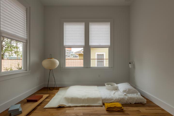 White walled minimalist room with a mattress on the floor and limited furnishings