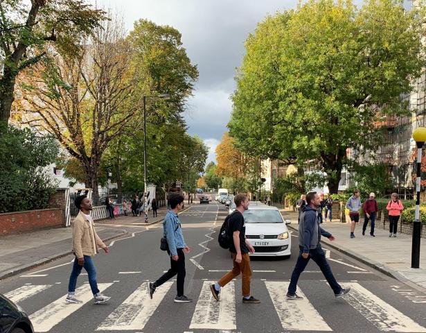 Four students walk along the Abbey Road crosswalk in the UK