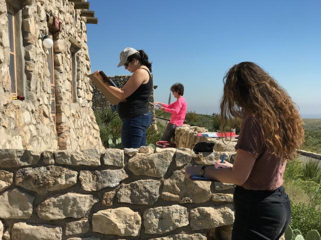 Students drawing and making notes outside a historic stone structure