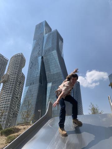 Student "surfing" on a slide in front of a skyscraper in Mexico City