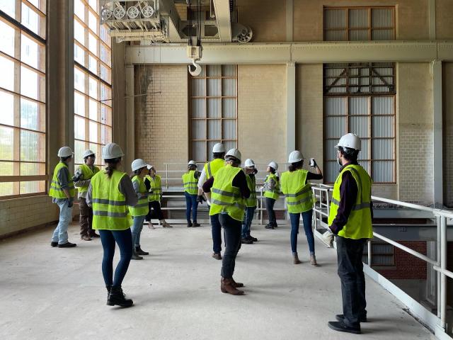 Students standing in a group wearing hard hats and neon yellow construction vests