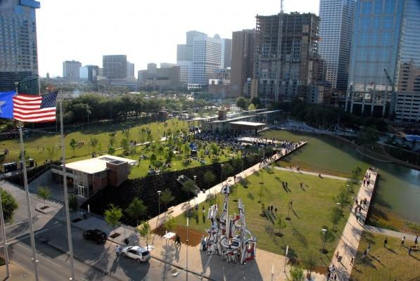 A plaza and park with office buildings in the background with an American flag in the foreground