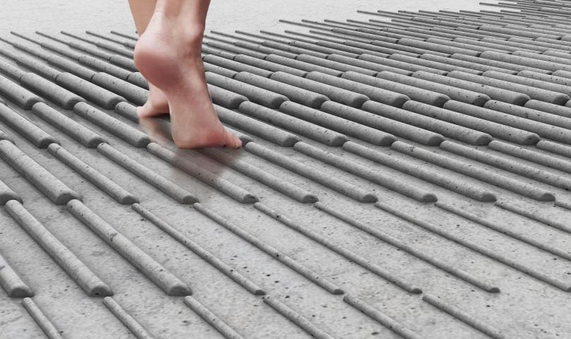The back of someones foot seen walking over a textured, moist ground
