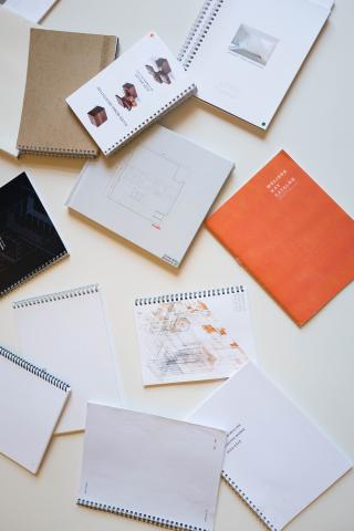 Overhead shot of several papers and student portfolios spread out on a table.