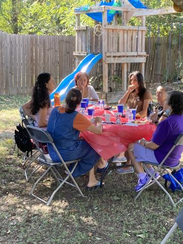 Climate Navigators eating outside in a backyard in front of a child's playhouse and slide