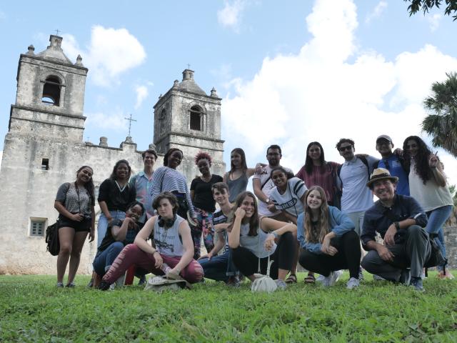 A group shot of students kneeling in front of a historic church