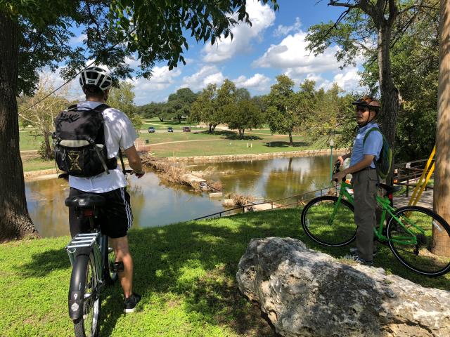 Professor Ming Zhang and a CRP student on bikes in front of a pond in Georgetown