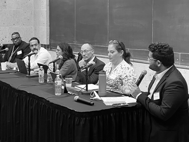 Black and white image of panelists speaking on the topic of homelessness in Austin