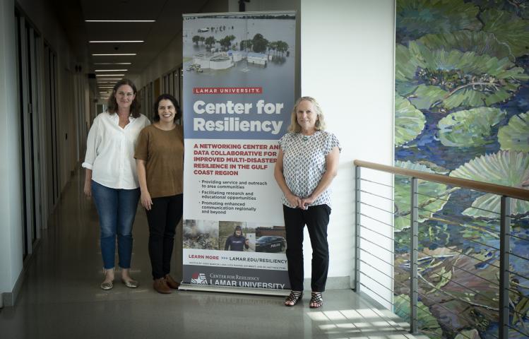 Katherine Lieberknecht and two others stand in front of a sign that reads "Center for Resiliency."