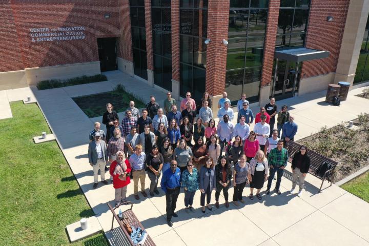 A group of people standing in a group outside seen from above.