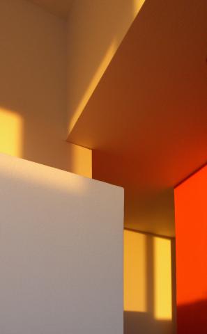 Sunlight casting shapes against white, yellow, and red painted walls