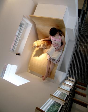 Woman and dog reading a book in a curved wooden reading nook 