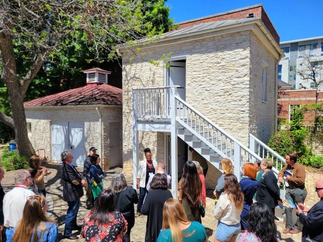 Tara Dudley with a crowd of attendees in front of the slave quarters at the Neill-Cochran House Museum.