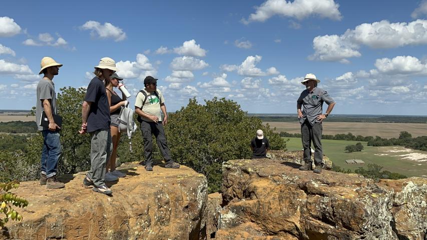 Students and faculty standing on boulders at a site visit