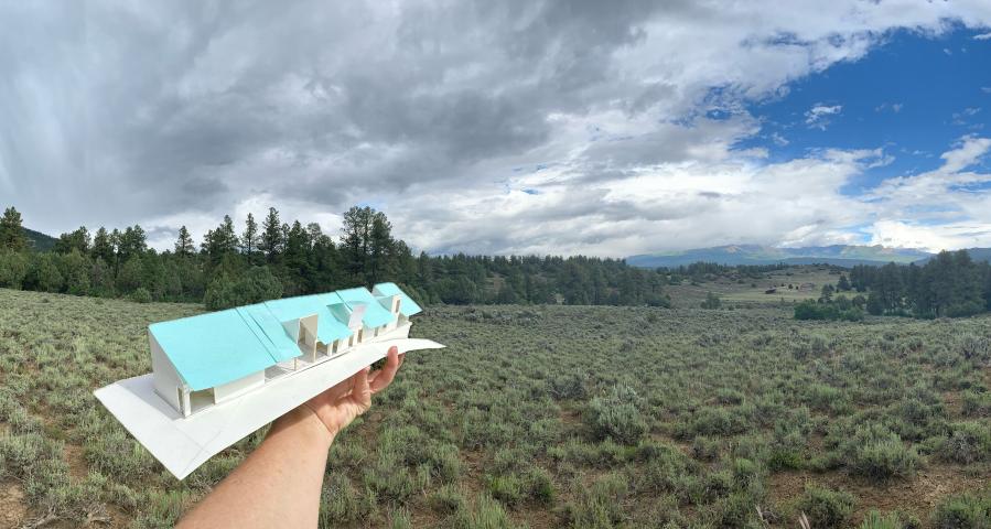 Hand holding an architectural model in front of a valley
