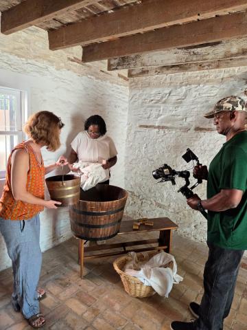 three people around a bucket in a historical room 
